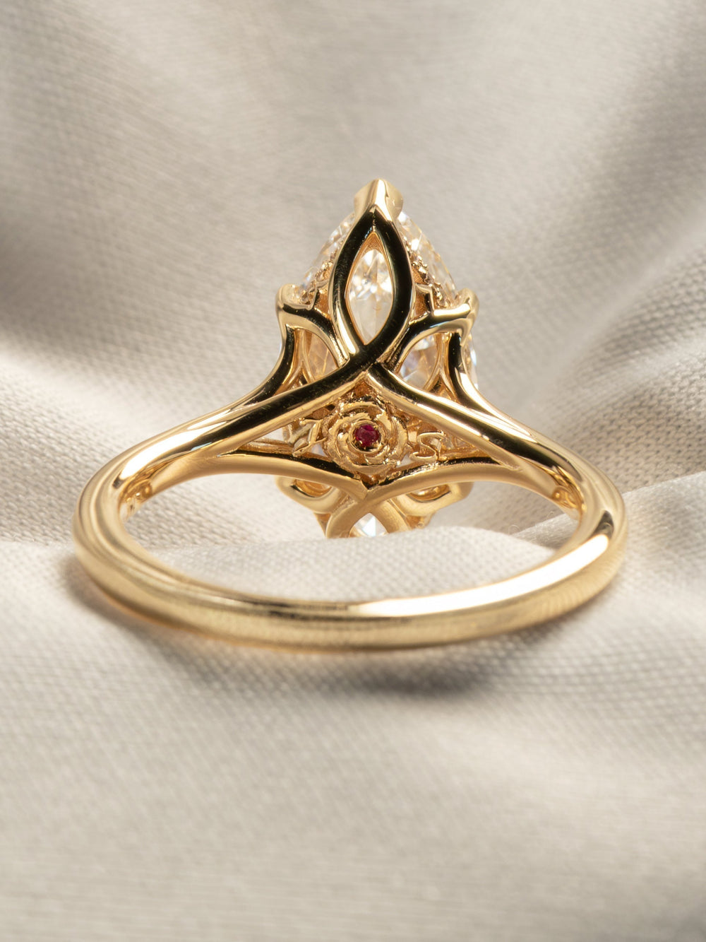 Back view of a gold floral head engagement ring with crossed petals and a hidden rose-and-ruby detail beneath a marquise diamond, handcrafted by Minhè by James Ly